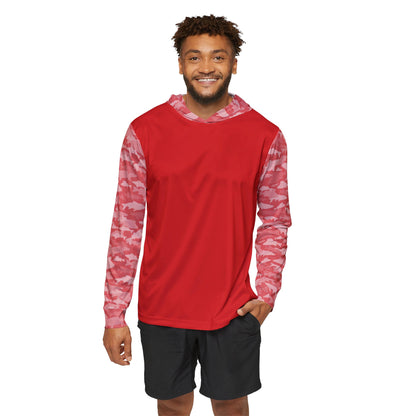 A person in a red CastAway Camo Sun Protection Hoodie UPF +50, featuring pink camouflage-patterned sleeves, smiles while standing against a plain white background, paired with black shorts.