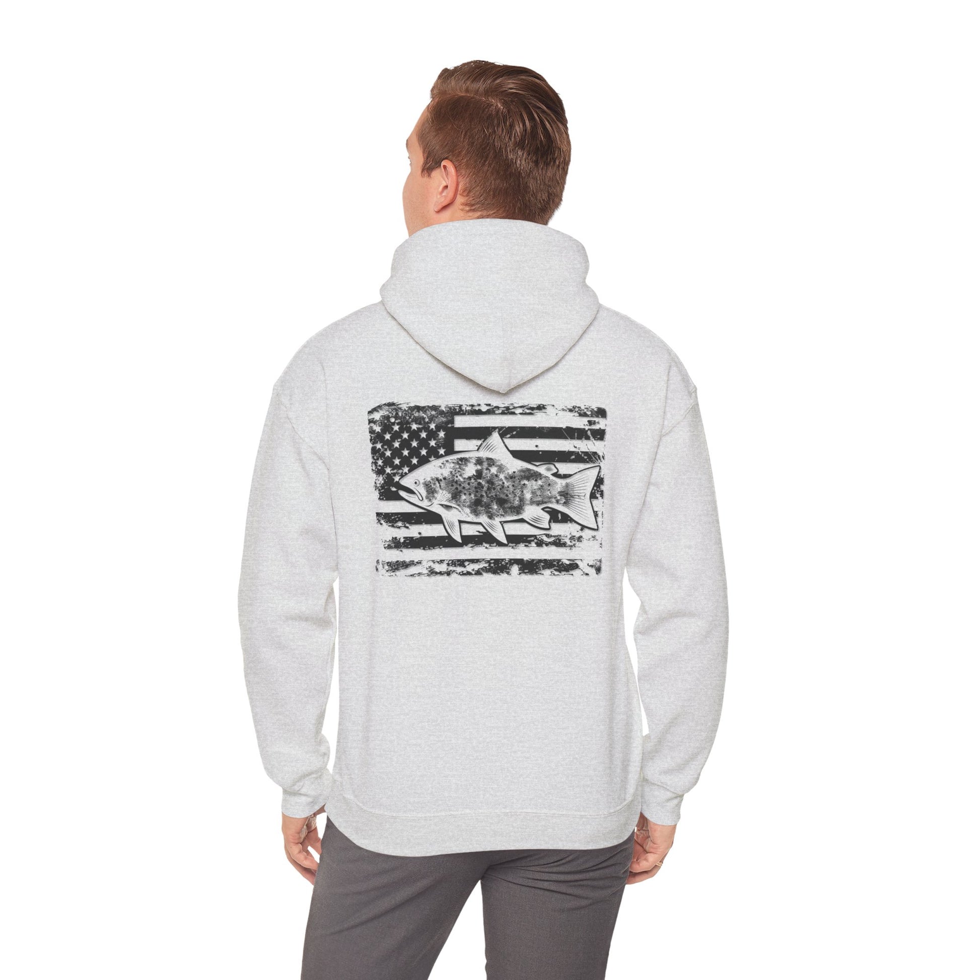 The Reeling In Freedom - Cotton/Poly Blend - Hoodie, ideal for any fishing enthusiast, is depicted from the front and back. The front showcases a small fish graphic accompanied by "Feeling of Freedom" text on the left chest, while the back prominently features a large fish graphic set against a distressed American flag design, celebrating American pride.