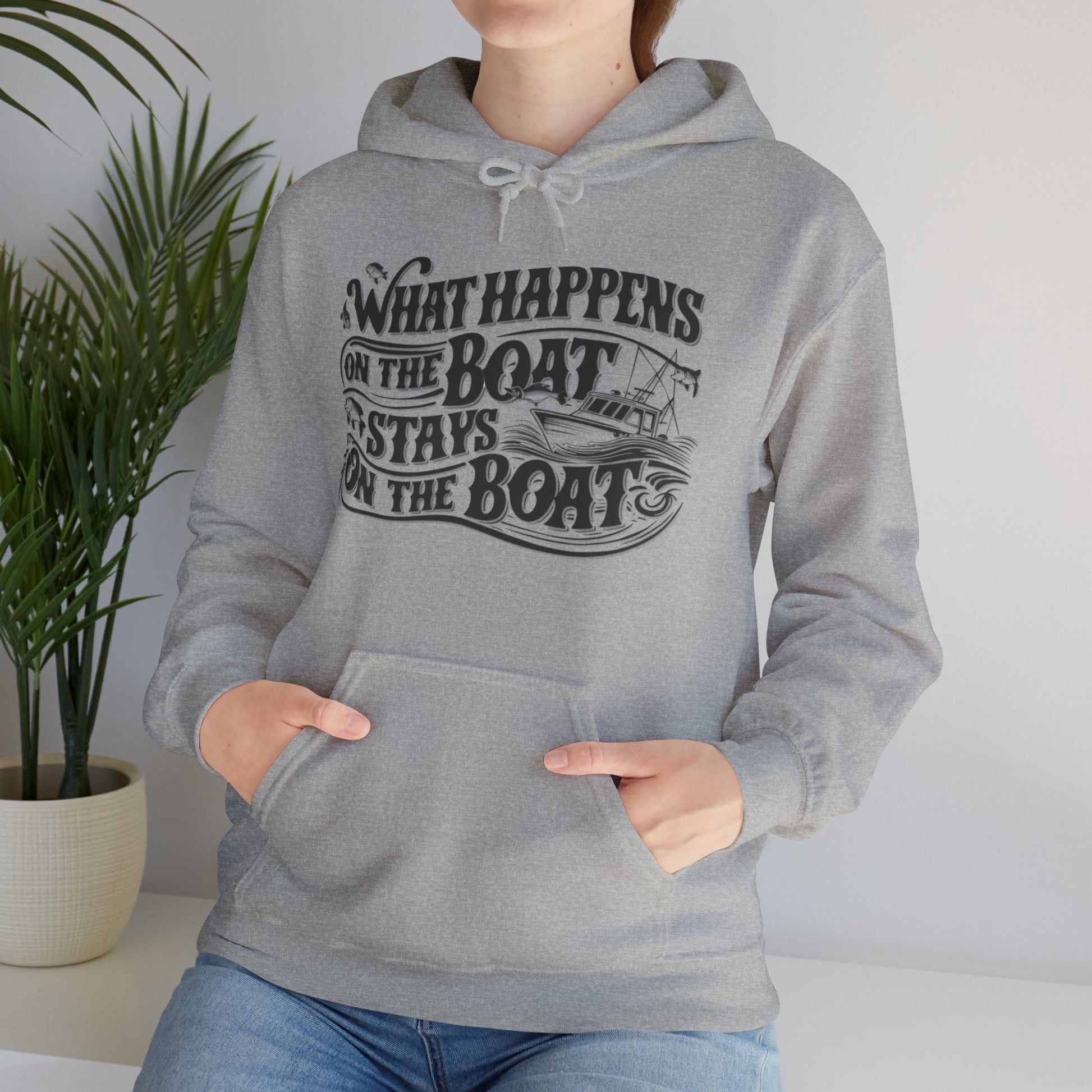 What Happens on the Boat, Stays on the Boat - Cotton/Poly Blend Hoodie - 7 Color Choices featuring white text that says "What Happens on the Boat Stays on the Boat" with fishing hooks and a boat illustration integrated into the design. The unisex hooded sweatshirt has a front pocket and drawstring hood, perfect for those with an adventurous spirit.