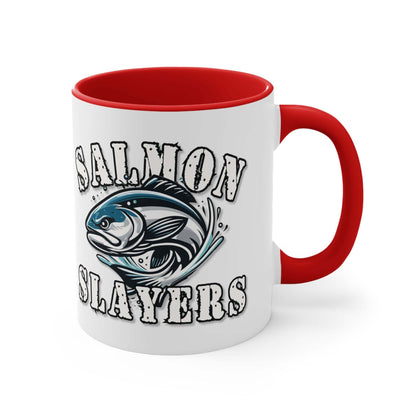 A white custom Salmon Slayers - Fierce Flash - Accent Coffee Mug, 11oz with a blue interior and C-handle features the design "Salmon Slayers" with a stylized illustration of a salmon in the center. The mug, showcasing an eye-catching color contrast, is placed on a wooden surface next to a small macaron, coffee beans, and a spoon.