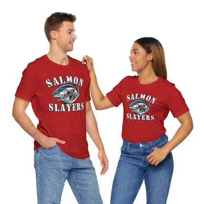 A blue unisex T-shirt made from 100% Airlume cotton featuring the text "Salmon Slayers" in bold, white, distressed letters. Below, an illustration of a fierce-looking fish with sharp teeth and dynamic lines suggests movement. Enjoy fast shipping on this striking design: **Slamon Slayers - Fierce Flash - T-Shirt**.