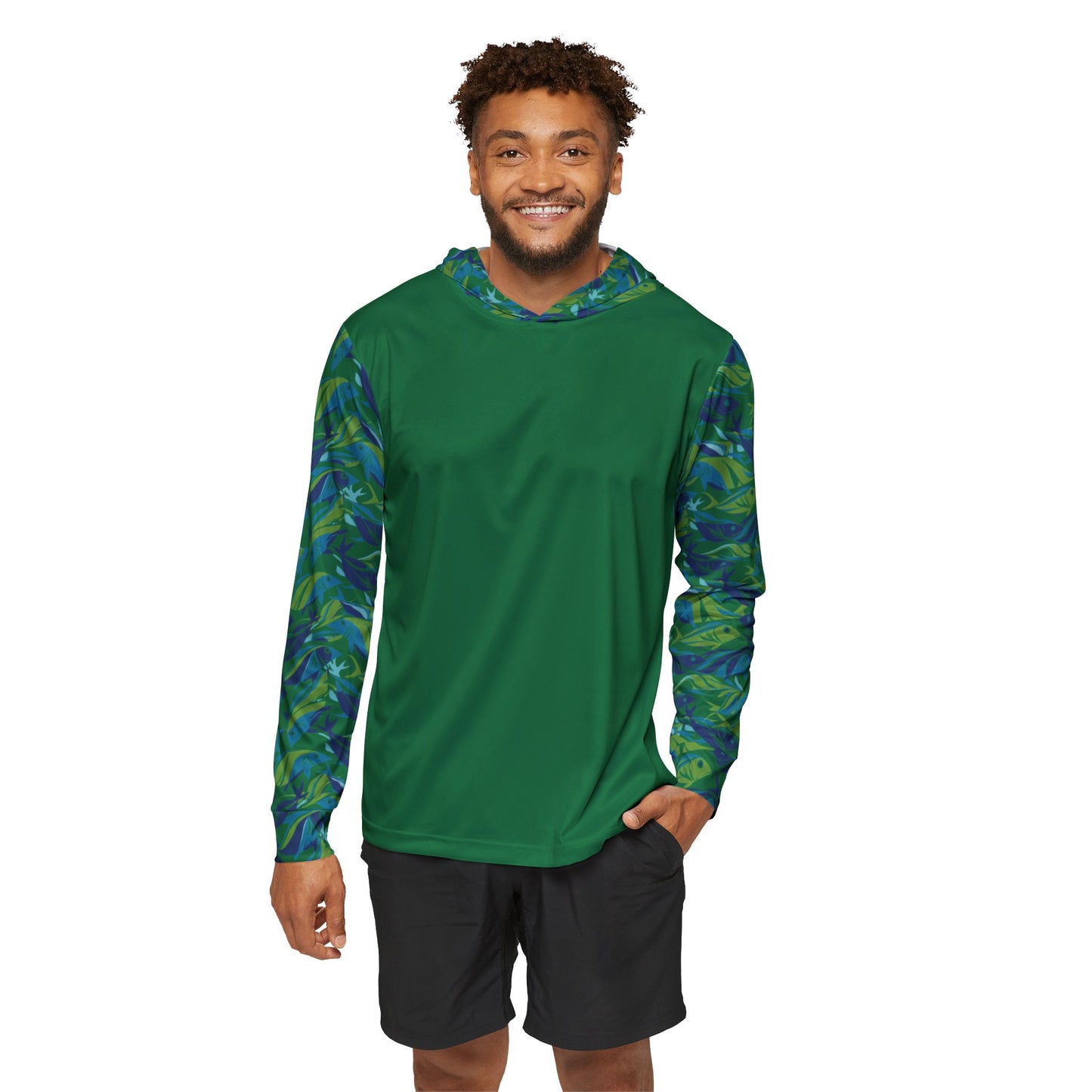 A man wearing the Whimsical Fish Sun Protection Hoodie UPF +50 in green, featuring blue and green patterned sleeves, smiles while standing against a white background. Crafted from moisture-wicking polyester, this hoodie pairs perfectly with his black shorts for both style and practicality.