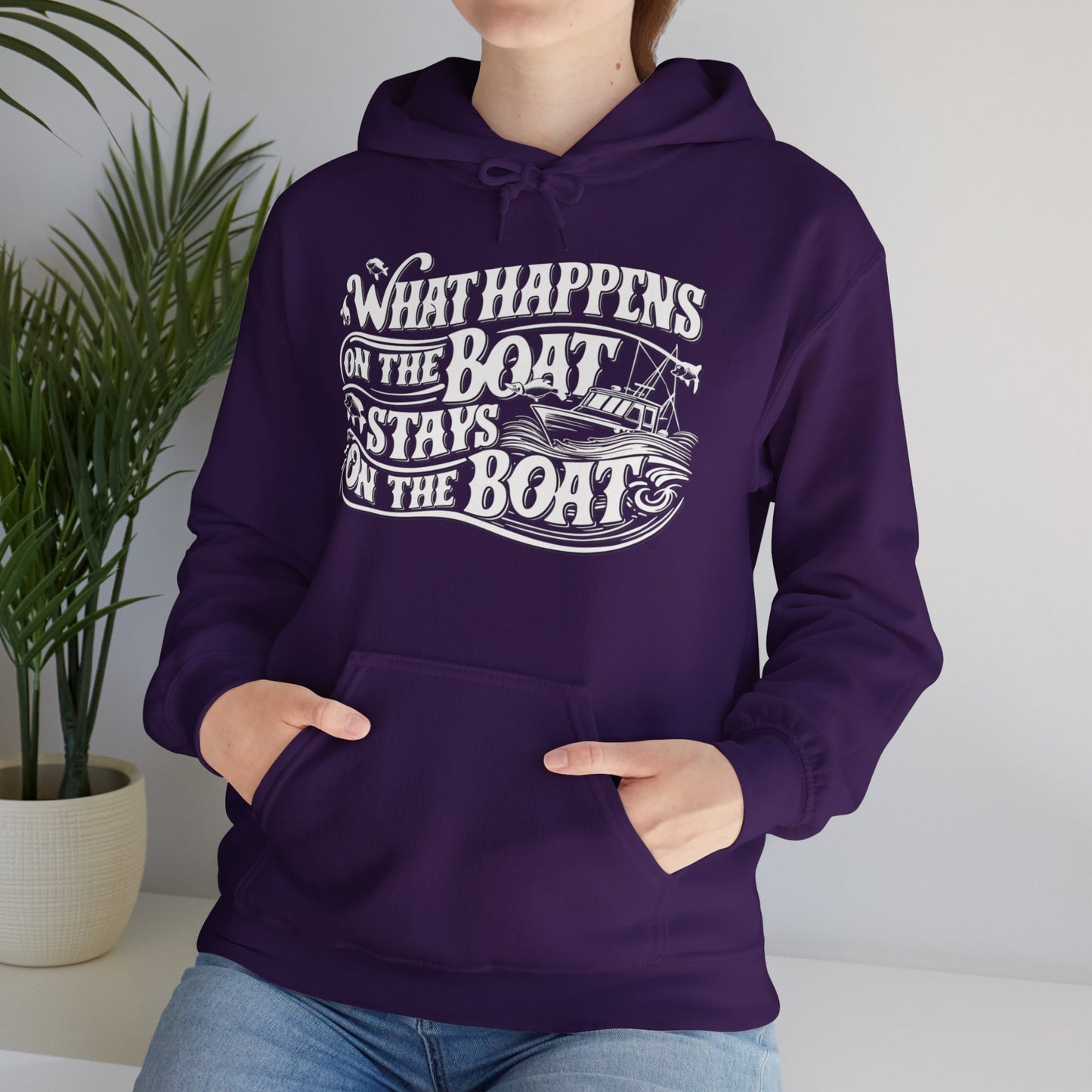 What Happens on the Boat, Stays on the Boat - Cotton/Poly Blend Hoodie - 7 Color Choices featuring white text that says "What Happens on the Boat Stays on the Boat" with fishing hooks and a boat illustration integrated into the design. The unisex hooded sweatshirt has a front pocket and drawstring hood, perfect for those with an adventurous spirit.