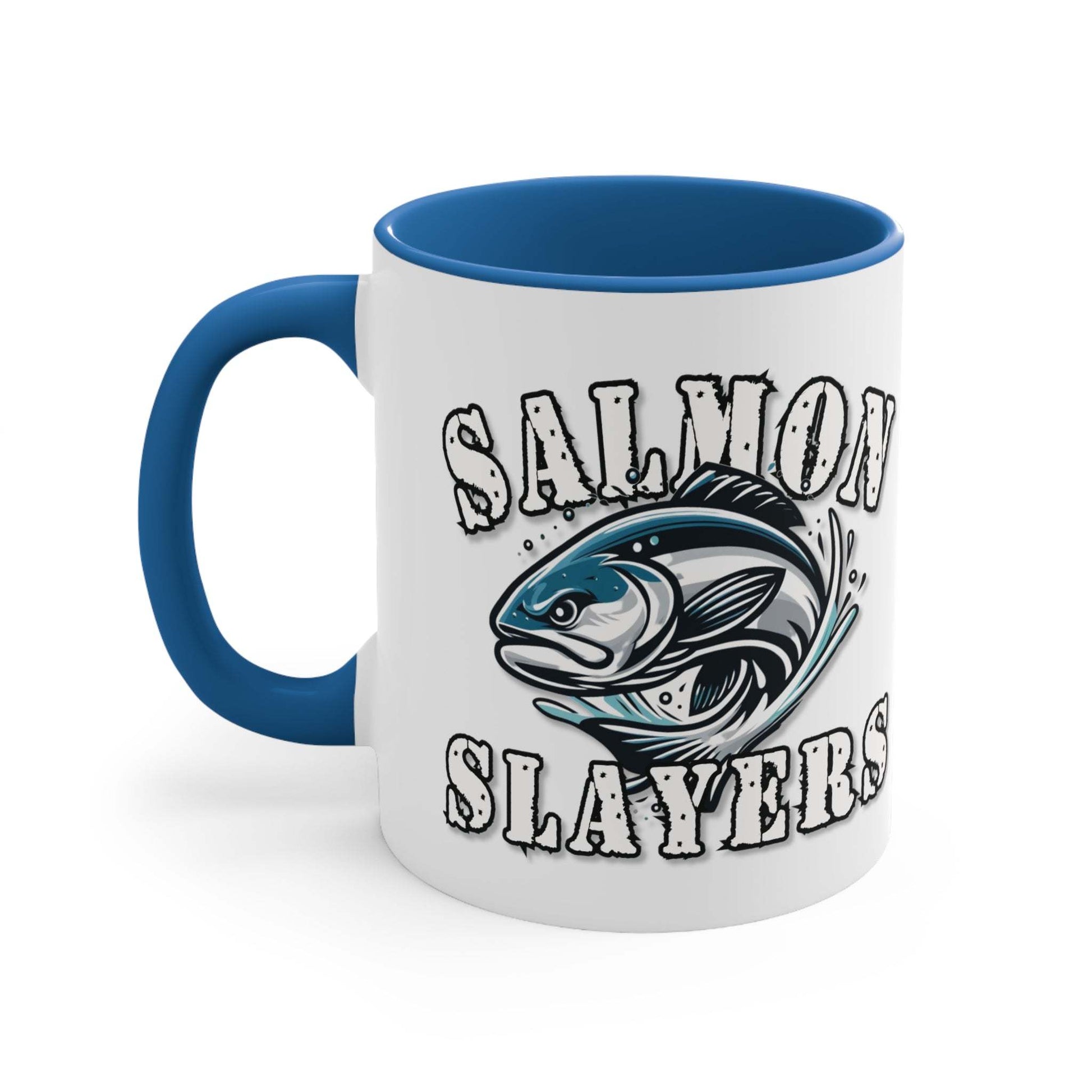 A white custom Salmon Slayers - Fierce Flash - Accent Coffee Mug, 11oz with a blue interior and C-handle features the design "Salmon Slayers" with a stylized illustration of a salmon in the center. The mug, showcasing an eye-catching color contrast, is placed on a wooden surface next to a small macaron, coffee beans, and a spoon.