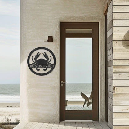 Customizable laser-cut steel sign with a crab monogram design on a beach house exterior.