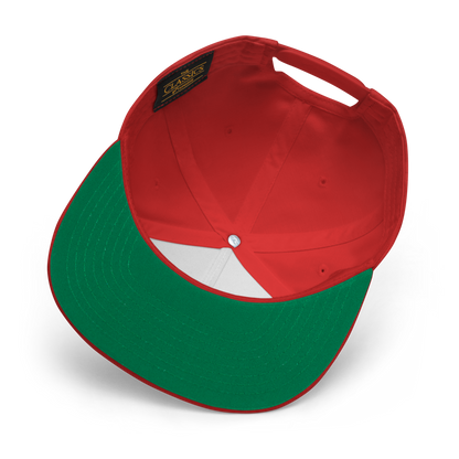 The image showcases the underside of the Salmon Slayers - Flat Bill Cap, which features a red crown with a green brim and snapback closure. Made from cotton twill, the interior is adorned with a black label featuring gold text, white lining under the crown, and a central metal button. The cap is artfully displayed against a black background.