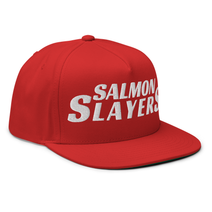 The Salmon Slayers - Flat Bill Cap is a red cotton twill snapback featuring bold white embroidered "SALMON SLAYERS" text on the front. It has a flat brim and secure snapback closure, shown against a plain black background.