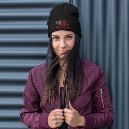 The "Fishing Flag - Embroidered Beanie" is a gray hat featuring a unique patriotic design on the front. The design resembles the American flag, with white stars on a blue background in the top left corner and horizontal red stripes made up of fish, instead of the traditional solid stripes.