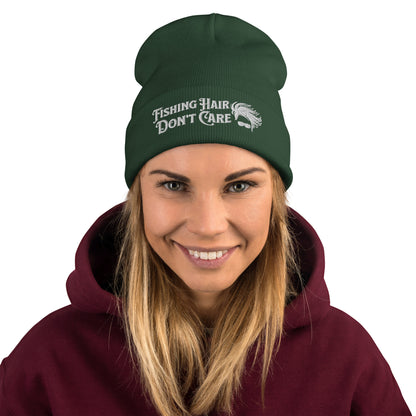 A black Beanie - Fishing Hair Don't Care with a snug fit and the text "Fishing Hair Don't Care" embroidered in white. The design is complemented by a simple graphic of curly hair and sunglasses.