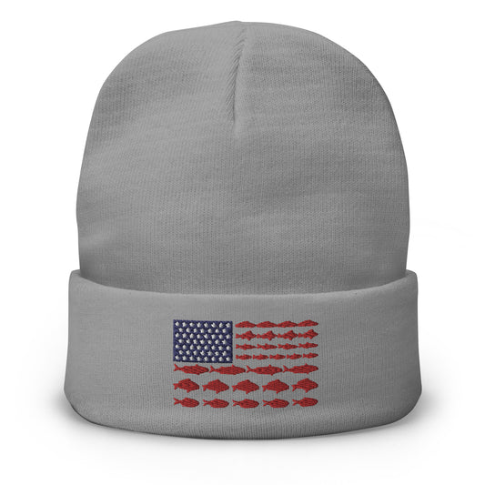 The "Fishing Flag - Embroidered Beanie" is a gray hat featuring a unique patriotic design on the front. The design resembles the American flag, with white stars on a blue background in the top left corner and horizontal red stripes made up of fish, instead of the traditional solid stripes.