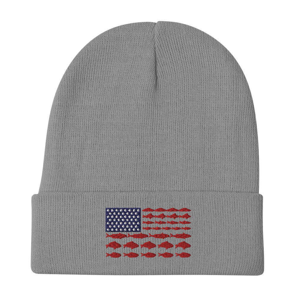 The "Fishing Flag - Embroidered Beanie" is a gray hat featuring a unique patriotic design on the front. The design resembles the American flag, with white stars on a blue background in the top left corner and horizontal red stripes made up of fish, instead of the traditional solid stripes.