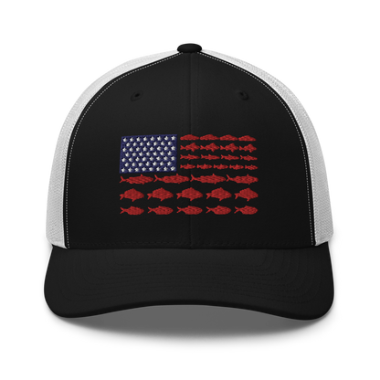 This Fishy Flag Trucker Cap is a black baseball cap featuring an American flag design made up of fish. The blue and white stars section is in the top left, while the red stripes are composed of small fish silhouettes, making it perfect for fishing enthusiasts.