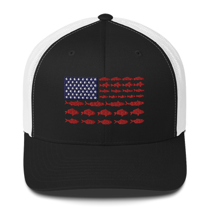 This Fishy Flag Trucker Cap is a black baseball cap featuring an American flag design made up of fish. The blue and white stars section is in the top left, while the red stripes are composed of small fish silhouettes, making it perfect for fishing enthusiasts.