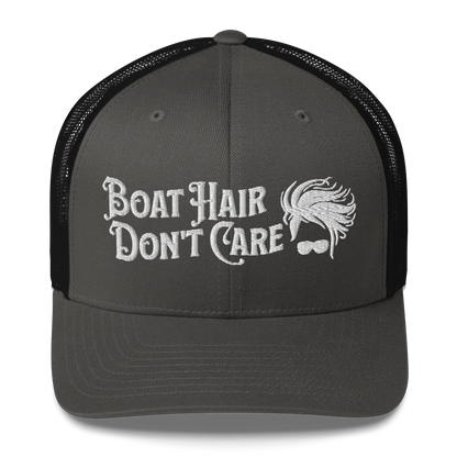 A Boat Hair, Don't Care - Trucker Style Fishing Cap with white mesh backing featuring the embroidered text "Boat Hair Don't Care" alongside a stylized illustration of hair blowing in the wind and a pair of sunglasses, making it the perfect fishing cap for your next adventure.