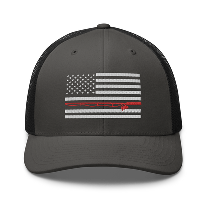 A black Fishing Flag Trucker Cap with an embroidered design of the American flag in white and gray. One of the horizontal stripes is red and features a silhouette of a bass fish. The flag design is centered on the front panel of this fishing enthusiasts hat.