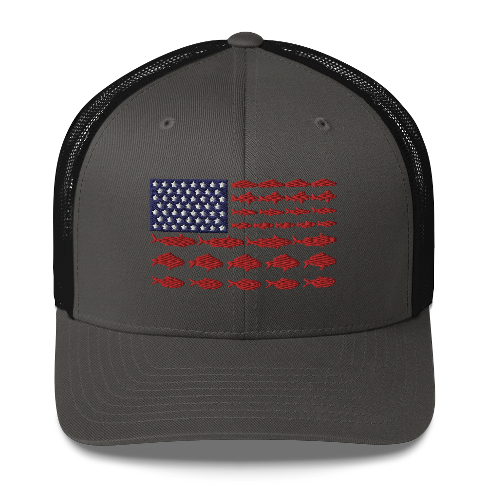 This Fishy Flag Trucker Cap is a black baseball cap featuring an American flag design made up of fish. The blue and white stars section is in the top left, while the red stripes are composed of small fish silhouettes, making it perfect for fishing enthusiasts.