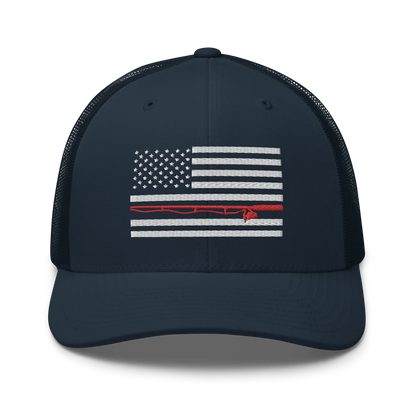 A black Fishing Flag Trucker Cap with an embroidered design of the American flag in white and gray. One of the horizontal stripes is red and features a silhouette of a bass fish. The flag design is centered on the front panel of this fishing enthusiasts hat.