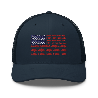 This Fishy Flag Trucker Cap is a black baseball cap featuring an American flag design made up of fish. The blue and white stars section is in the top left, while the red stripes are composed of small fish silhouettes, making it perfect for fishing enthusiasts.