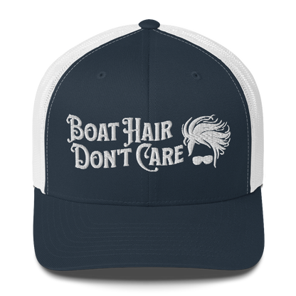 A Boat Hair, Don't Care - Trucker Style Fishing Cap with white mesh backing featuring the embroidered text "Boat Hair Don't Care" alongside a stylized illustration of hair blowing in the wind and a pair of sunglasses, making it the perfect fishing cap for your next adventure.