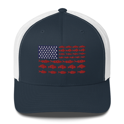 This Fishy Flag Trucker Cap is a black baseball cap featuring an American flag design made up of fish. The blue and white stars section is in the top left, while the red stripes are composed of small fish silhouettes, making it perfect for fishing enthusiasts.