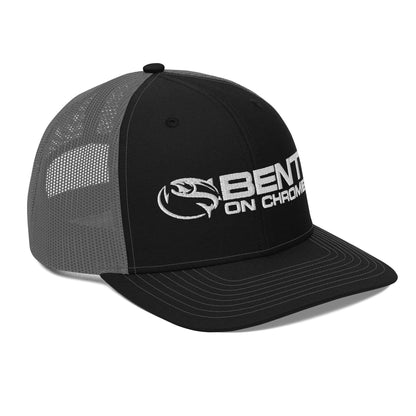 A black and gray Bent on Chrome - Richardson 112 Trucker Cap with Puffer Embroidery featuring the logo "bent on chrome" with a stylized wing design on the front panel. The cap has a mesh back, an adjustable snap