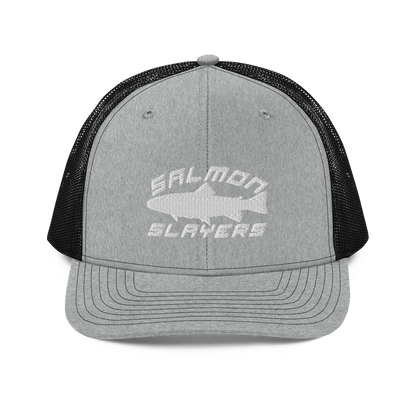 A Salmon Slayers - Sport - Richardson 112 - Trucker Cap with the text "SALMON SLAYERS" embroidered in white on the front. Above the text, there is an outline of a salmon fish. The cap features stitching details on the brim and offers a structured fit. The background is solid black.