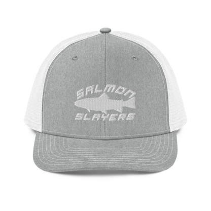 A Salmon Slayers - Sport - Richardson 112 - Trucker Cap with the text "SALMON SLAYERS" embroidered in white on the front. Above the text, there is an outline of a salmon fish. The cap features stitching details on the brim and offers a structured fit. The background is solid black.